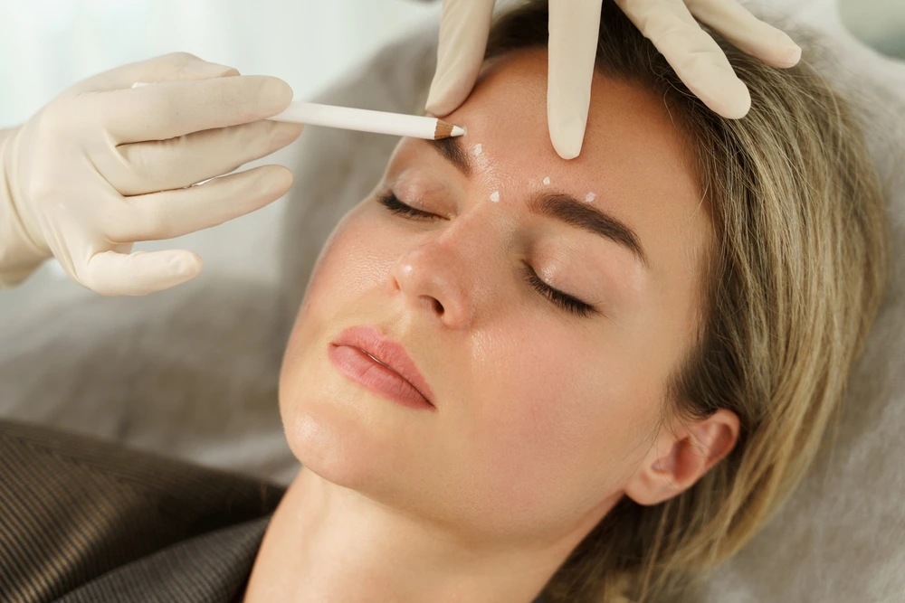 Doctor applying marking for forehead facial aesthetics